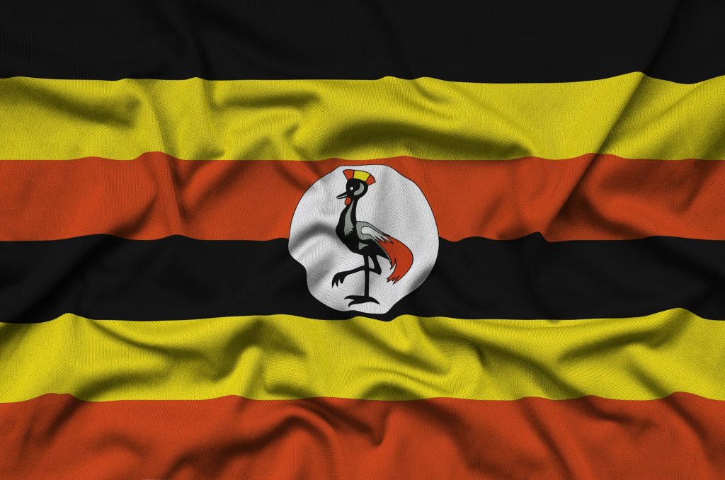 Uganda flag is depicted on a sports cloth fabric with many folds. Sport team waving banner